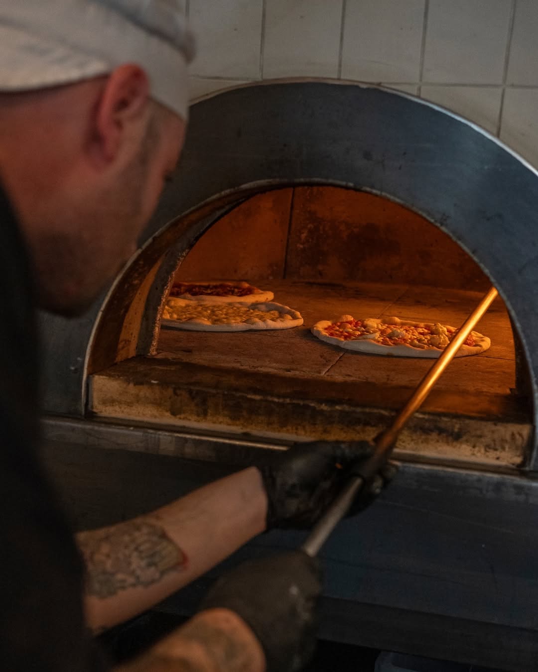 Pizzaiolo metiendo pizzas al horno