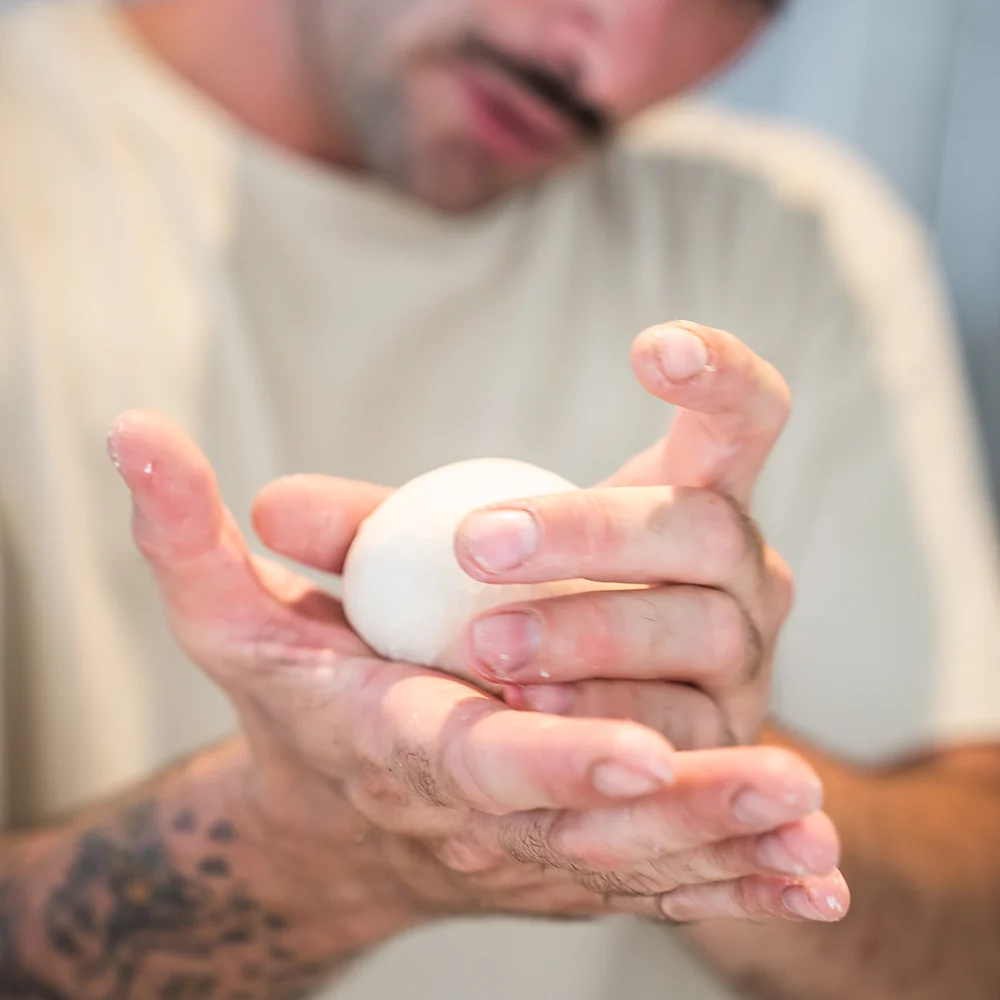 Bola de mozzarella fresca escurriendo entre las manos