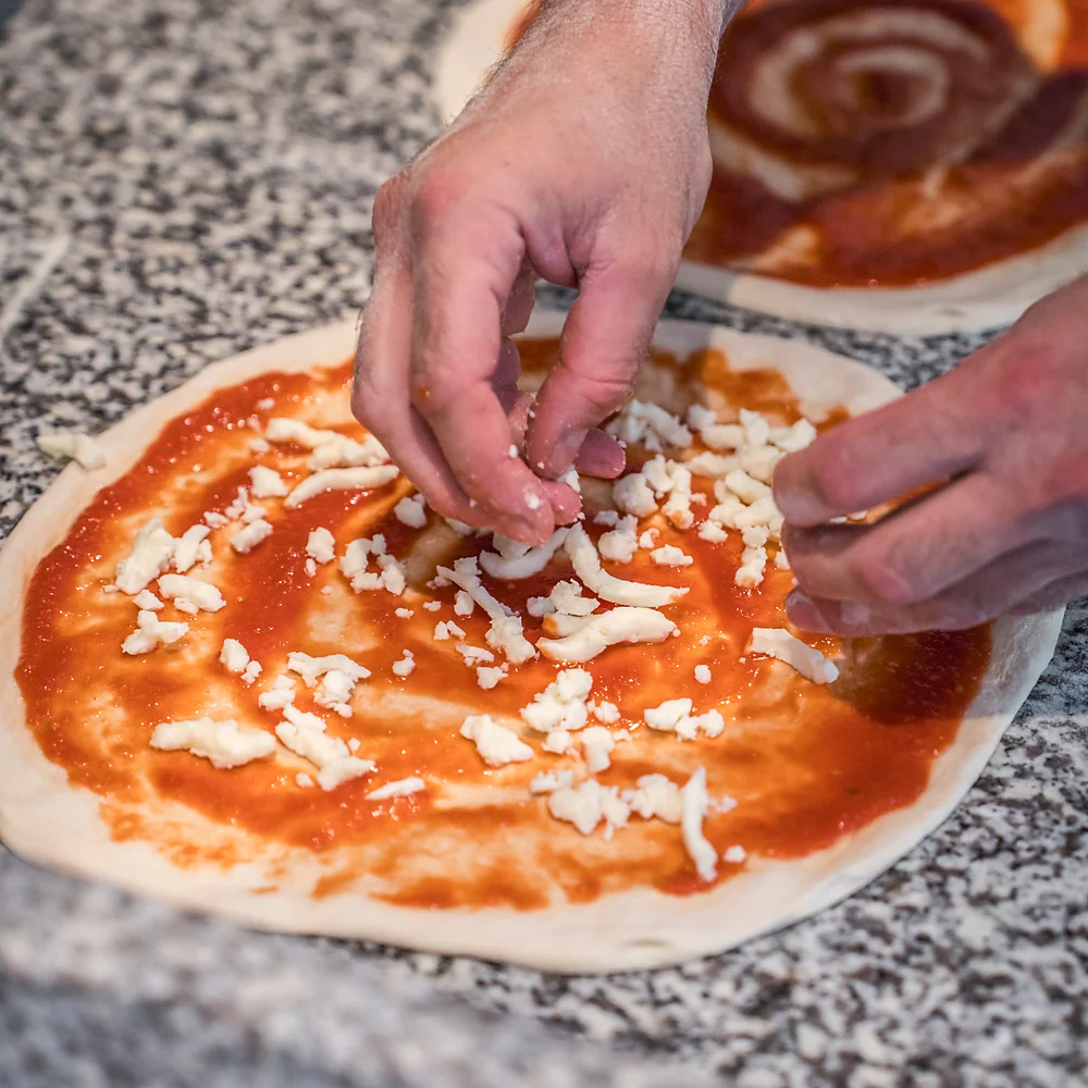 Repartiendo mozzarella sobre la masa de pizza